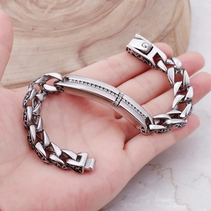 Men's titanium steel cross bracelet with diamonds on wrist against a marble background