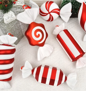 Close-up of red and white candy Christmas ornaments on white lace with festive props