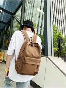 Close-up of a brown canvas backpack showing padded straps and durable multi-pocket design