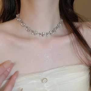 Close-up of heart-shaped pearl necklace with pink zircon on model's neckline