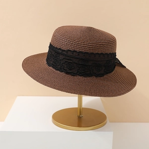Detail of the woven straw sun hat texture with elegant black floral lace trim decoration