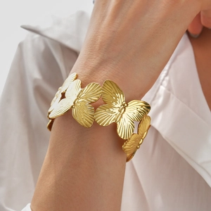 Close-up of golden butterfly cuff bracelet with detailed embossed wing texture on wrist