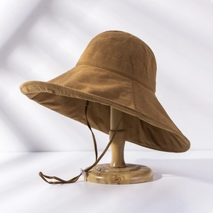 Detail of wide brim canvas sun hat in tan with adjustable chin strap on wooden stand