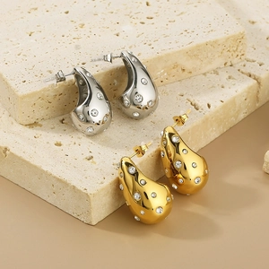 Detailed view of teardrop earrings with crystals in gold and silver finish on stone