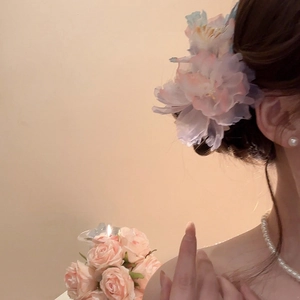 Dettaglio di un grande fermaglio per capelli a fiore in rete sfumata con perle su uno chignon