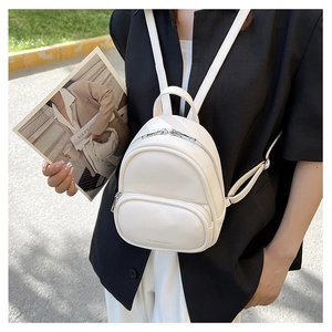 Chic white mini backpack held by model in professional suit, sleek PU leather texture