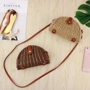 Semicircle straw crossbody bags in light and dark brown on a wooden desk background