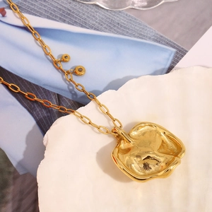Detail der 18K vergoldeten Halskette mit unregelmäßigem Metallanhänger auf Muschel