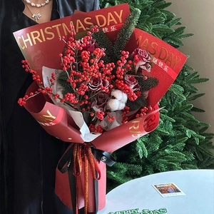 Christmas bouquet in red gold-foil wrapping paper with holly berries and pine branches