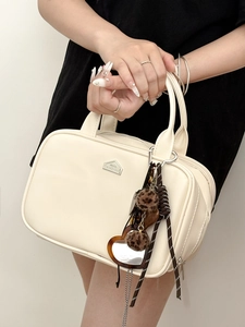 Detail of luxury white leather handbag with puppy charm and decorative accessories