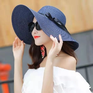 Cappello da sole in paglia blu scuro a tesa larga con fiocco nero su una modella