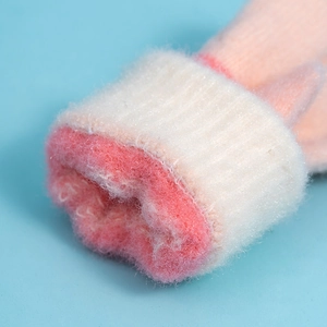 Close-up of warm knitted kids gloves with soft pink plush lining and ribbed cuffs