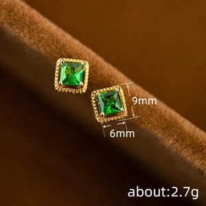 Vintage gold square zircon stud earrings with green gemstones on brown velvet background