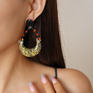 Close-up of bohemian teardrop earrings with gold foil inside transparent resin