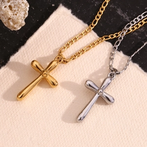 Detailed view of polished gold and silver cross pendants on a figaro chain necklace