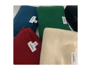 Detail of ribbed knit scarves in navy, green, burgundy and beige with branded woven labels