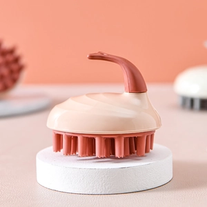 Silicone scalp massage brush in beige and brown on a white pedestal with soft background