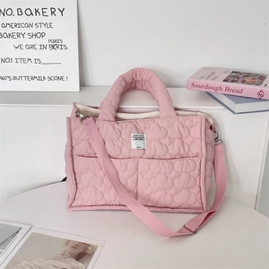 Dettaglio ravvicinato della borsa trapuntata rosa con tracolla regolabile e etichetta