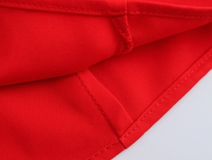 Gros plan sur la texture du tissu rouge et les coutures de l'ourlet à volants de l'ensemble