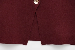 Gros plan sur maille bordeaux avec un bouton ambre et détail de fente sur l'ourlet