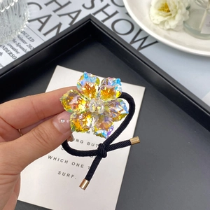 Detailed close-up of a dual-layer crystal flower hair tie with a black elastic band