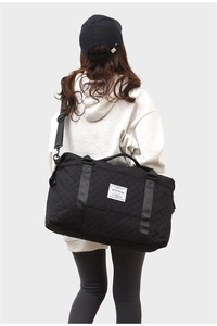 Rear view of a model wearing the large black quilted fitness travel bag with shoulder strap