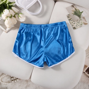 Flat lay of blue satin sports shorts with white piping, pearls and luxury accessories