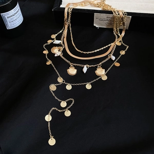 Detailed close-up of layered gold shell necklace with sequins on black background