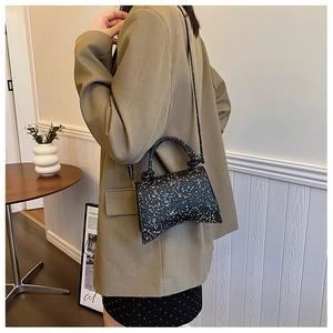 Detailed view of black sequined crossbody bag with a unique curved base and star pattern