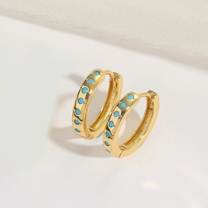Detail of gold-plated twisted hoop earrings with light blue turquoise-style stone inlays