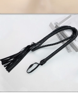 Detail of a black faux leather braided whip with fringe tassel and hand strap loop