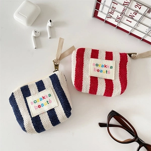 Close-up of mini striped canvas makeup pouches with zipper and woven handle detail