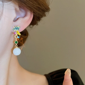 Détail de boucles d'oreilles émaillées fleurs avec pierres vertes et perles