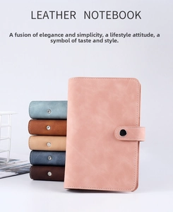 Stack of multi-colored leather binder notebooks featuring secure metal snap closure detail