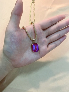 Detailed close-up of a square purple zircon pendant on a gold twisted rope chain necklace