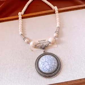 Vintage bohemian stone beaded necklace with a large round metal pendant and blue marble gem