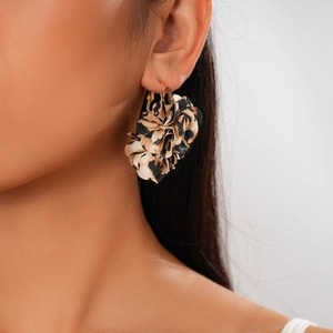 Close-up of leopard print fabric flower earrings with gold hooks worn by a model