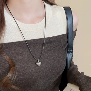 Polished silver heart pendant on minimalist black cord worn by model for daily wear