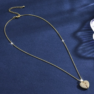 Polished gold heart pendant necklace with shimmering crystals on dark blue velvet background