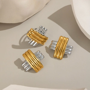 Detailed view of two-tone gold and silver striped crisscross earrings on a minimalist background