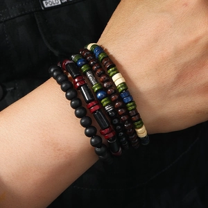 Close-up of men's multilayered beaded bracelets with wooden beads and metal accents