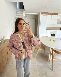 Detail of pink floral pattern quilted jacket featuring a front lace-up tie closure