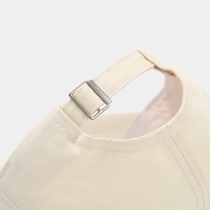 Detail of adjustable silver metal buckle and fine stitching on the beige cotton baseball cap