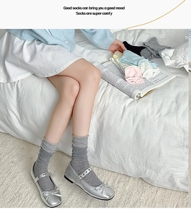 Close-up of grey knitted crew socks with layered cuffs on a model in a bedroom setting