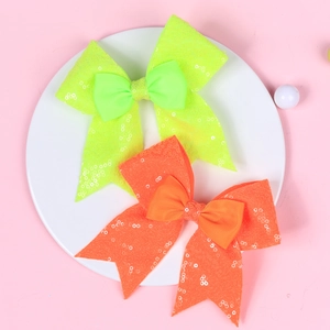 Detail view of large sequined bows in neon green and orange for girls' hair clips