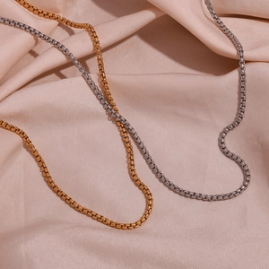 Detail of gold and silver stainless steel box chains on champagne silk fabric texture