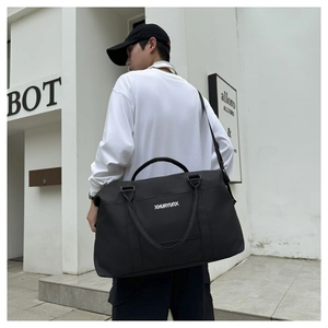 Side view of a large black oxford travel bag shown with a male model in casual street style