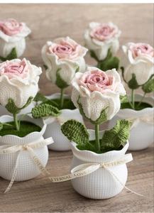Detailed close-up of handmade crochet rose plant with Love Is Eternal ribbon