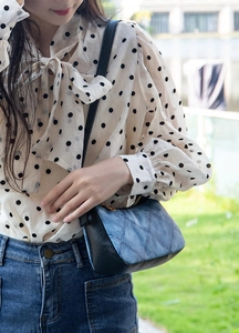 Detail of denim patchwork shoulder bag with black leather base and gold zipper accents
