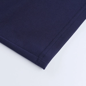 Detailed close-up of precise stitching on dark blue knitted dress hem and cuffs